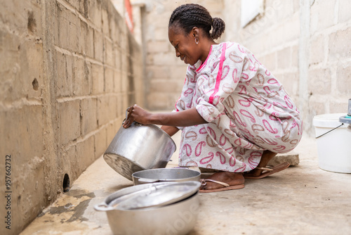 African woman washing dishes outside her home in senegal photo