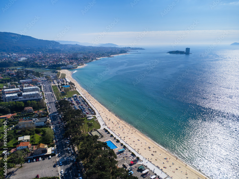 Aerial view of Playa de Samil, the main beach of Vigo in Galicia in northwest Spain. Sunny day, crystal clear blue sea. Houses, streets. Drone Aerial view of Playa de Samil, the main beach of Vigo in Galicia in northwest Spain. Sunny day, crystal clear blue sea. Houses, streets. Drone