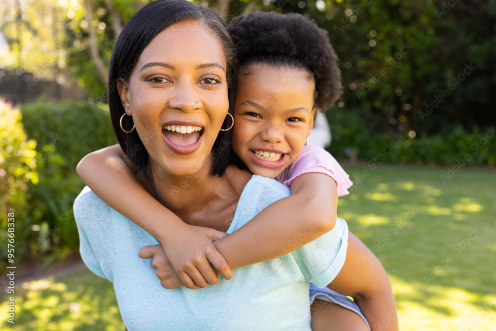 Smiling mother giving piggyback ride to daughter, enjoying time together outdoors Smiling mother giving piggyback ride to daughter, enjoying time together outdoors