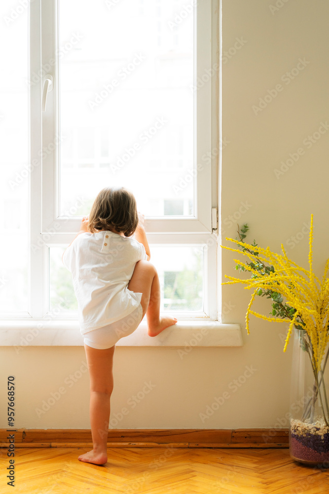 Little girl climbing on the window sill