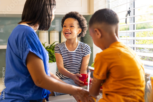 Mother and children in kitchen, smiling and preparing food together