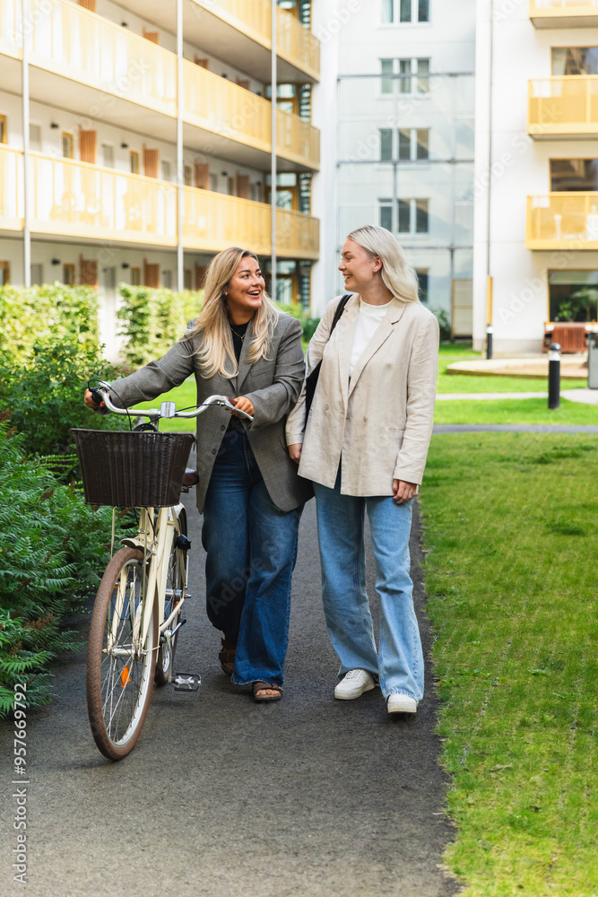 LGBT Woman Couple Walking Together with Bike in Neighborhood LGBT Woman Couple Walking Together with Bike in Neighborhood