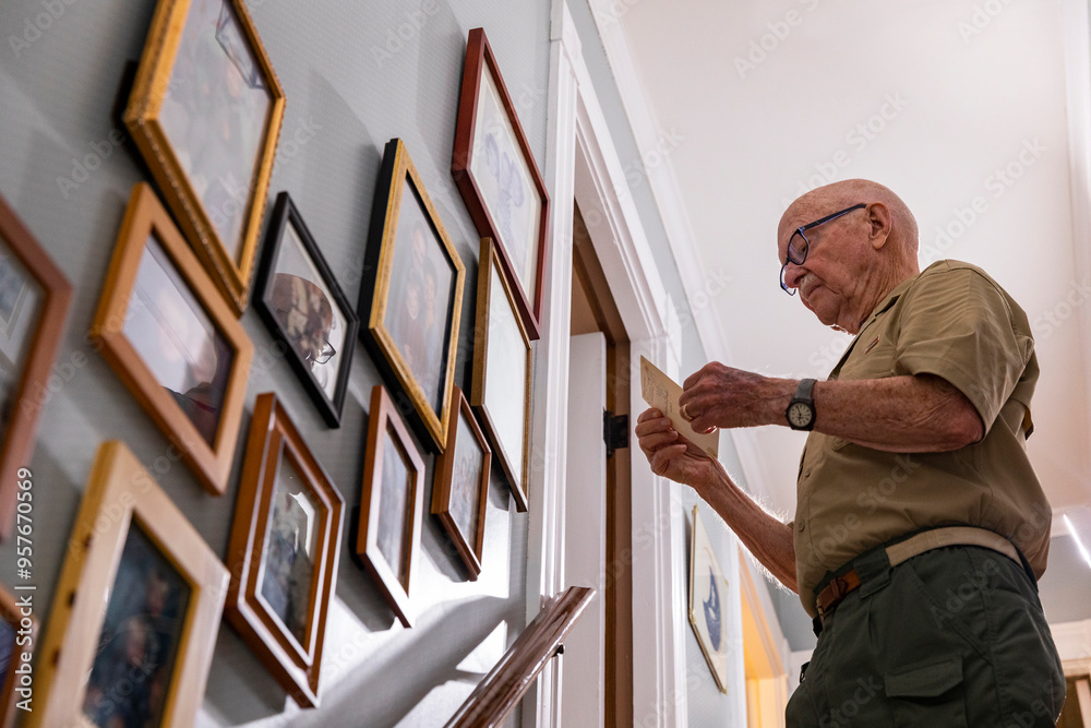 Active Senior Citizen military looking at old photographs wall home Active Senior Citizen military looking at old photographs wall home