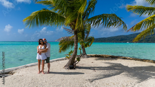 Romantic getaway from a married couple, The man and woman are hugging on a small tropical island with a sandy beach and tiny palm tree under blue sky. The people are surrounded by azure ocean sea 