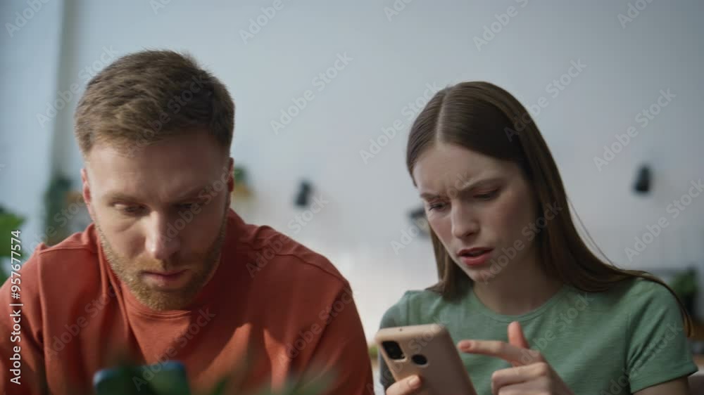 Spouses worried smartphone message sitting living room closeup. Serious family Spouses worried smartphone message sitting living room closeup. Serious family