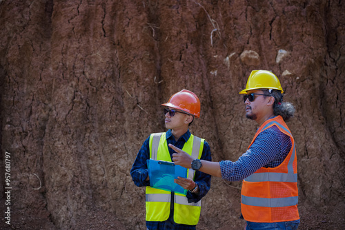 Two young male construction workers are surveying using blueprints in the field