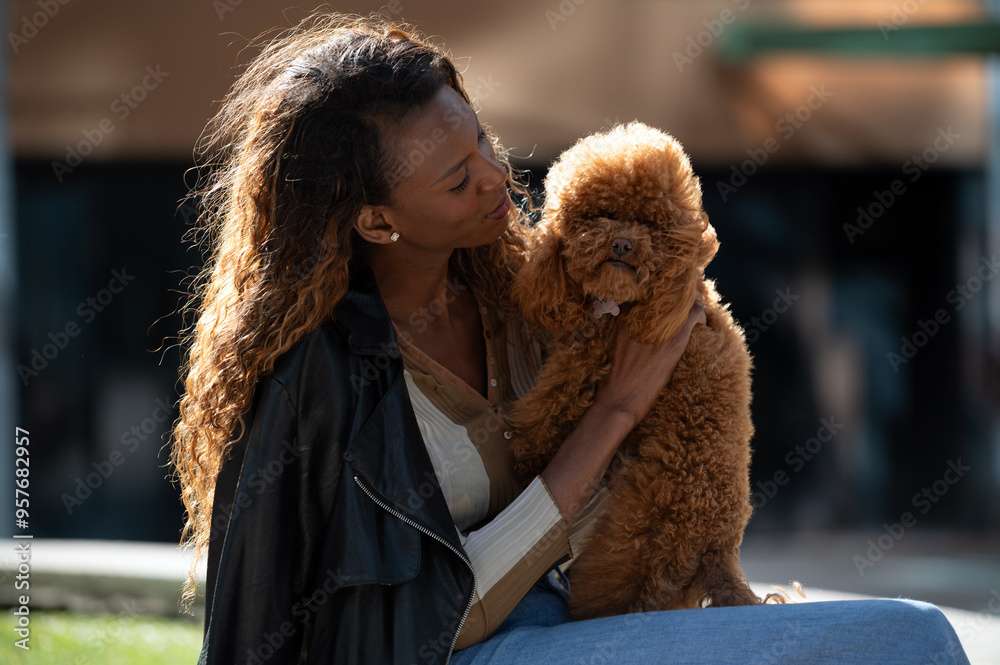 Woman lovingly embracing her fluffy poodle in sunlight