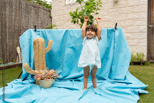 Baby girl raising arms on blue background photo