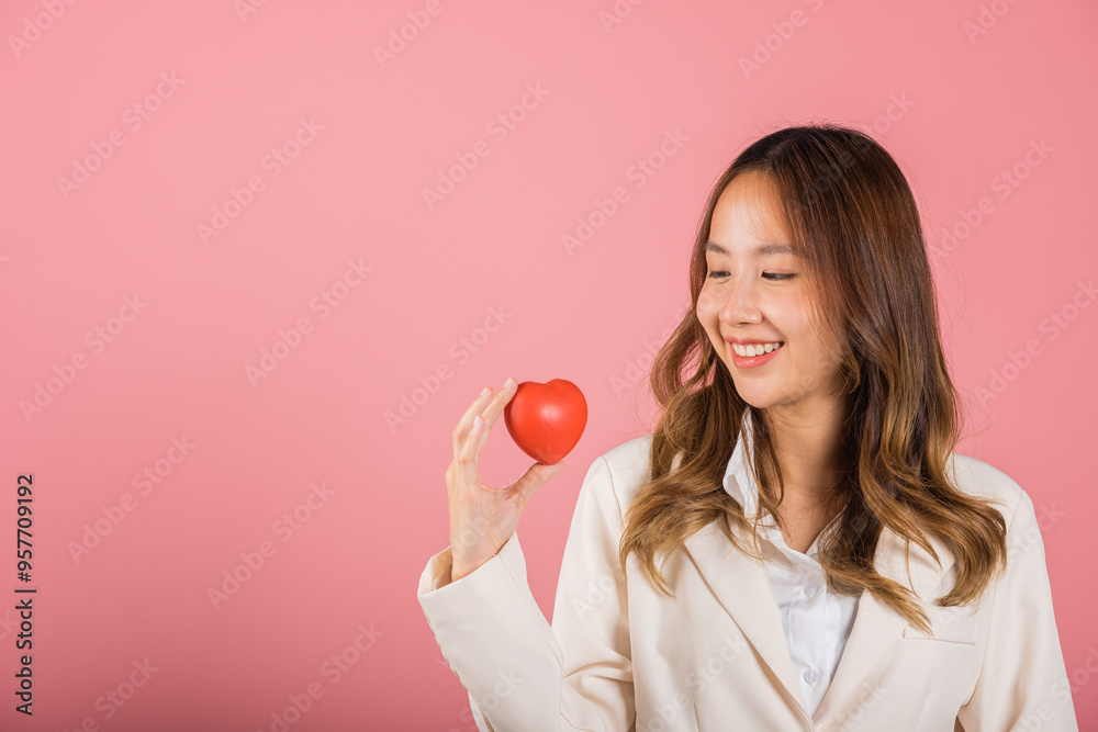 Smiling woman confidence showing holding red heart with her hand palm isolated pink background, Asian happy portrait beautiful young female send love and happy valentine in studio shot, copy space Smiling woman confidence showing holding red heart with her hand palm isolated pink background, Asian happy portrait beautiful young female send love and happy valentine in studio shot, copy space