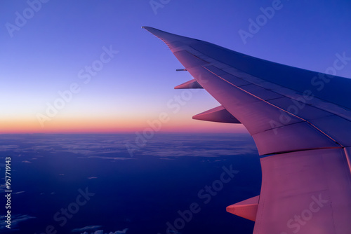 Airplane Wing Over Sunset-Hued Clouds at High Altitude