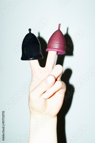 Hand holding menstrual period cups and showing peace sign with flash photo