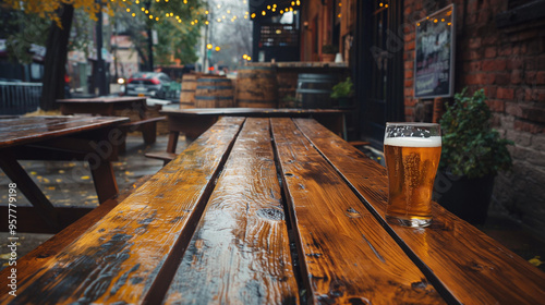 A pint of beer sits on a rustic wooden table at an outdoor pub setting, with an autumn evening ambiance.