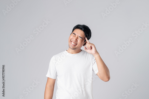 Portrait of young Asian man in casual white clothing, smiling joyfully as he contemplates something pleasant. Isolated on white background.