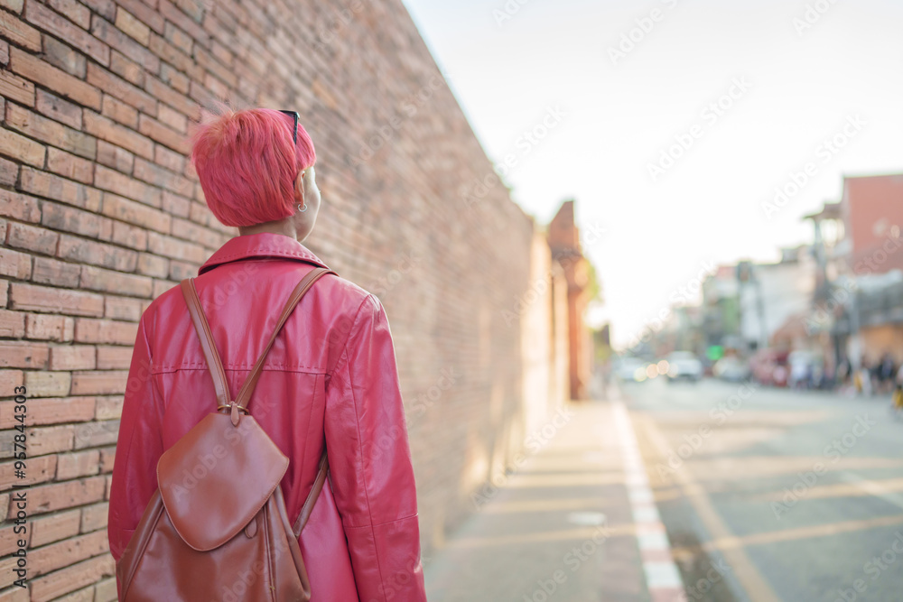 Fototapeta premium Gen z girl leather fashion with punk Asian woman tourist of local city Southeast Asia travel trendy pink hairstyle young female punk traveler walking around in town