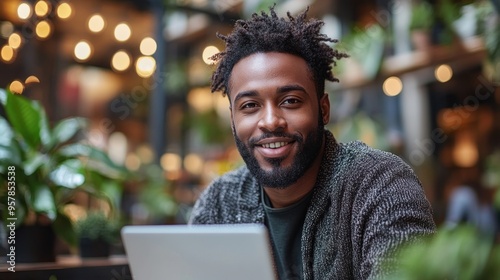 A man with a beard is smiling and holding a laptop