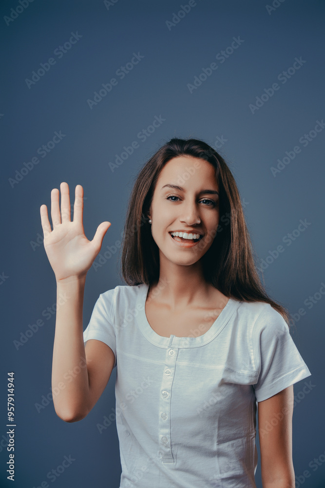 Young woman waving and smiling on blue background Young woman waving and smiling on blue background
