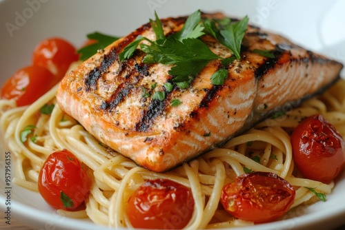 A plate of grilled salmon served on a bed of linguine pasta, garnished with fresh parsley