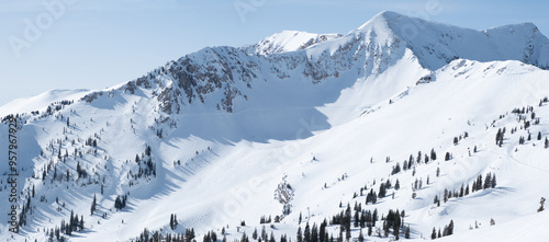 Massive mountain side with snow and traversing path for backcountry