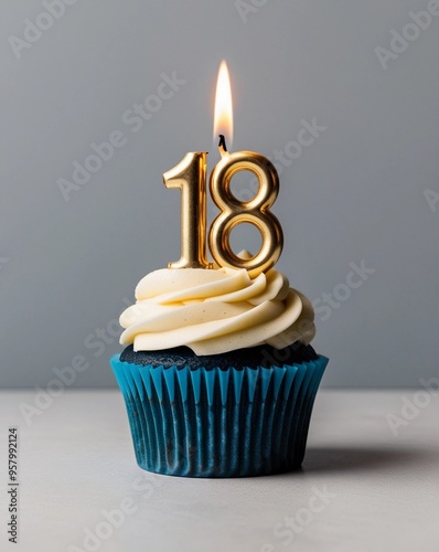 Blue Cupcake with White Frosting and Lit Gold Number Eighteen Candle
 photo