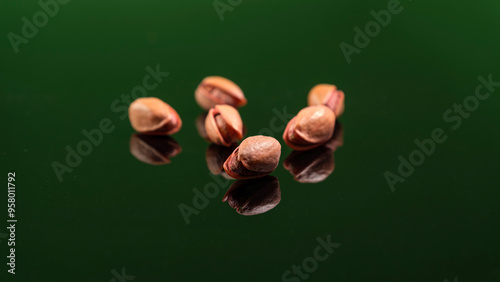 Close-up of organic Siirt pistachios on a reflective surface with a green background. Ideal for themes of healthy snacks, Turkish cuisine, and natural produce. photo