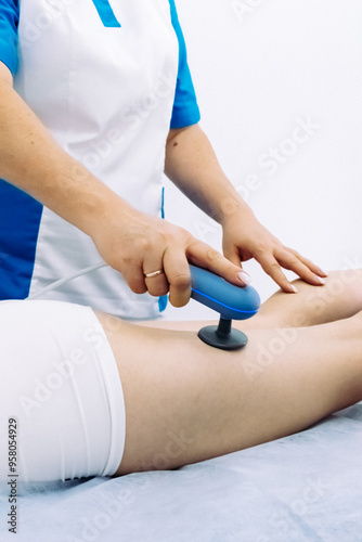 A doctor administers magnetic therapy to a young woman, targeting muscle recovery post-injury. Ideal for showcasing advanced physiotherapy treatments that accelerate healing and restore function.