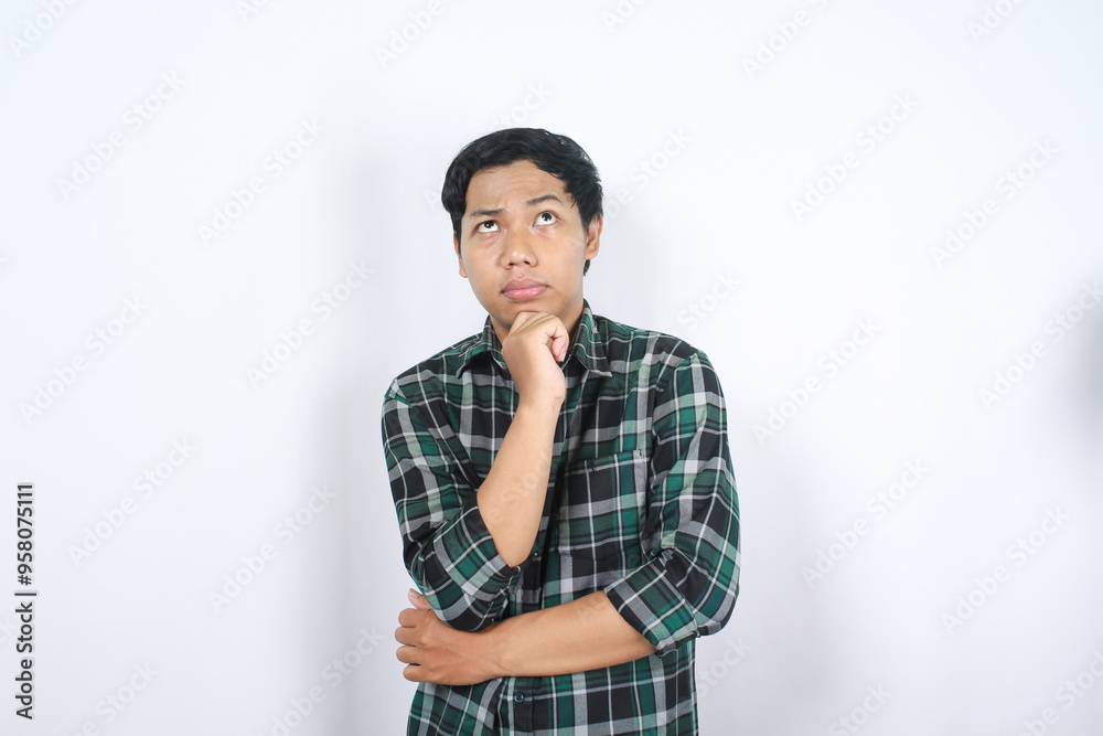 portrait of curious asian young man wearing casual clothes looking above with hand on chin thinking isolated on white background portrait of curious asian young man wearing casual clothes looking above with hand on chin thinking isolated on white background