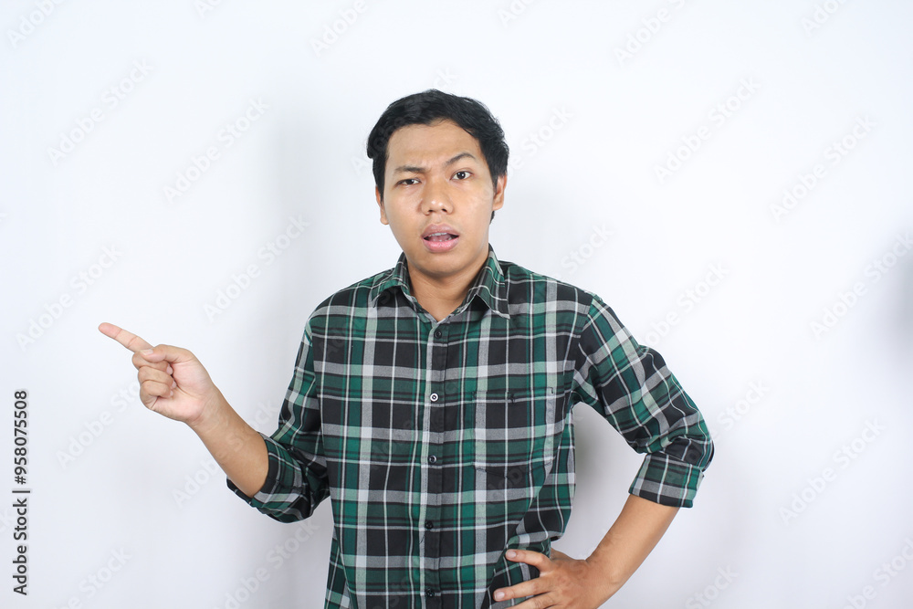 isolated attractive asian young man pointing beside to empty space with confused face and doubtful expression isolated attractive asian young man pointing beside to empty space with confused face and doubtful expression