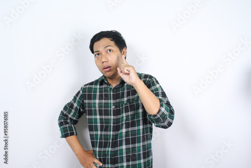 thoughtful asian young man isolated on white background thinking an idea with pointing finger up and looking above