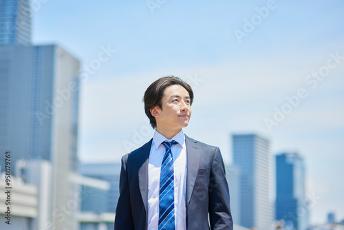 ビジネス街で遠くを見つめるスーツを着た若いビジネスマン