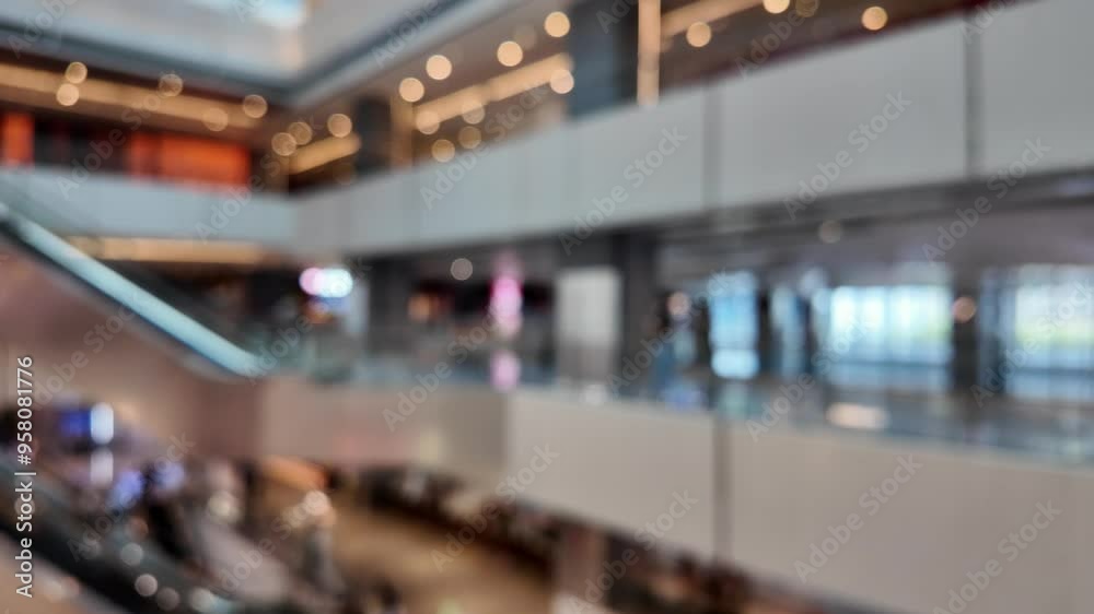 A blurry view from inside a modern shopping mall, showing an escalator and multiple levels with shops and light fixtures. A blurry view from inside a modern shopping mall, showing an escalator and multiple levels with shops and light fixtures.