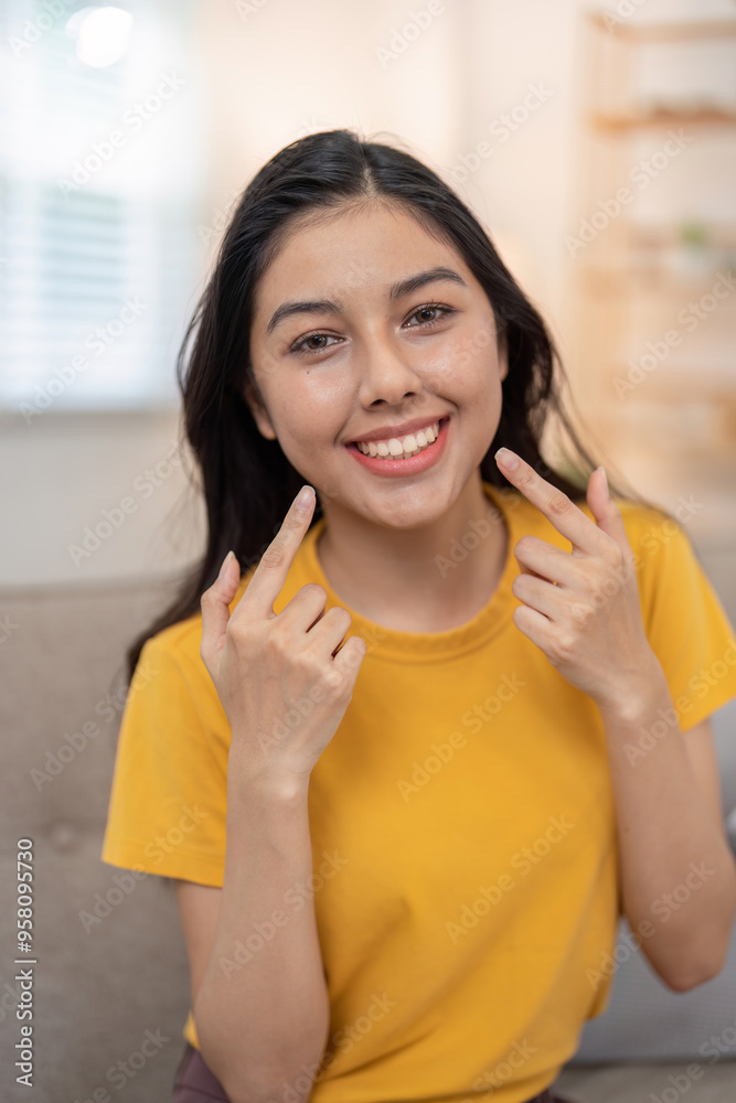 Confident young woman pointing at her beautiful smile Confident young woman pointing at her beautiful smile
