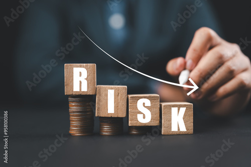 Risk wording on decreasing coins stacking with down arrow for financial banking risk analysis and management ,Low risk low return concept.