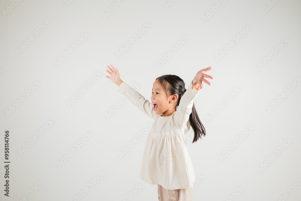 A jubilant kid girl raises her fists in celebration of her success, saying yes with excitement. Asian portrait of a happy young kindergarten child in a studio shot on a white background, winning A jubilant kid girl raises her fists in celebration of her success, saying yes with excitement. Asian portrait of a happy young kindergarten child in a studio shot on a white background, winning