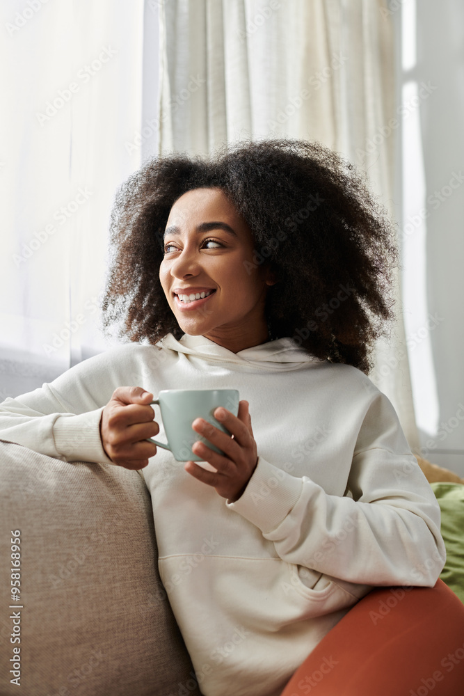 A young woman relaxes in her cozy living room with a warm drink, showing joy and comfort.