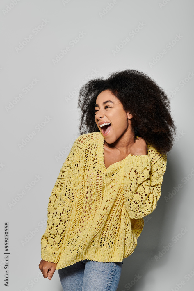 A young woman with curly hair smiles radiantly while wearing a vibrant yellow sweater. A young woman with curly hair smiles radiantly while wearing a vibrant yellow sweater.