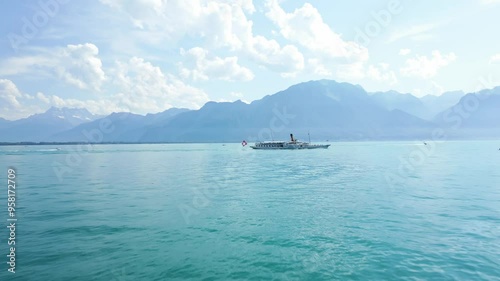 Big boat cruising on the Lake of Geneva with the Swiss Alps behind and a sunny weather.