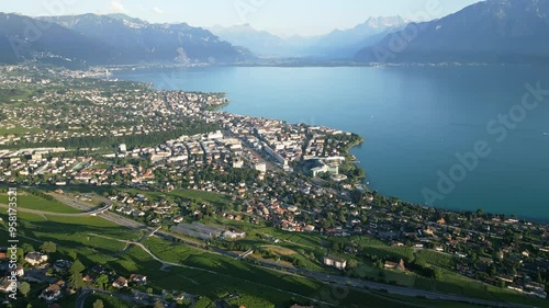 Reveal drone shot above Vevey in the Lavaux with the Lake of Geneva and the Swiss Alps behind.