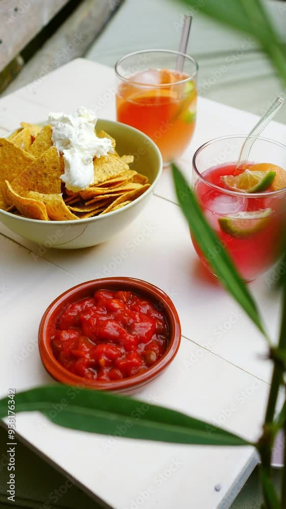 Fresh fruit cocktails with bowl of tortilla chips with red salsa dip and sour cream, vertical shot Fresh fruit cocktails with bowl of tortilla chips with red salsa dip and sour cream, vertical shot