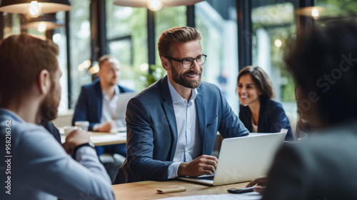 Business team meeting with focus on a smiling man using laptop