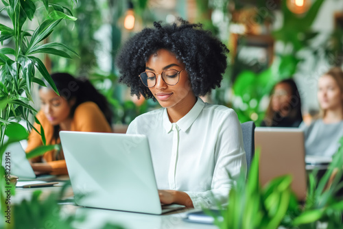 Young black woman working on laptop in modern office setting