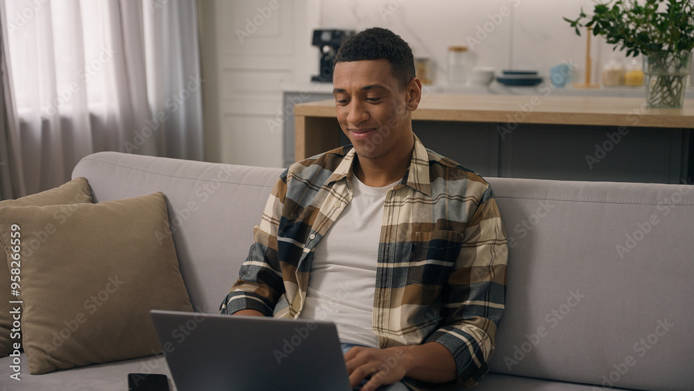Happy smiling African American ethnic man freelancer working at home distant online work at sofa smile positive student guy studying remote with laptop using computer e-learning at couch male using pc Happy smiling African American ethnic man freelancer working at home distant online work at sofa smile positive student guy studying remote with laptop using computer e-learning at couch male using pc