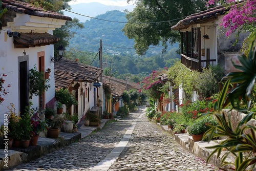 A picturesque cobblestone street in Cuetzalan, adorned with vibrant flowers and traditional houses under a clear blue sky. photo