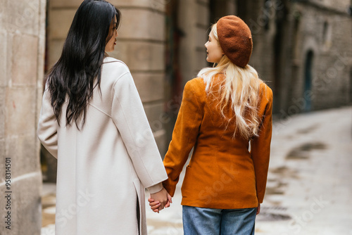 Photography Two female tourists holding hands are walking in a barcelona street
