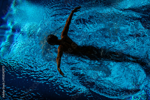 Female athlete swims with a butterfly style. Splashes of water scatter in different directions