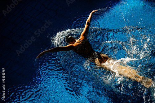 Female athlete swims with a butterfly style. Splashes of water scatter in different directions