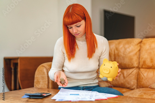 Contemplative Woman Counting Coins While Managing Expenses at Home With a Piggy Bank photo