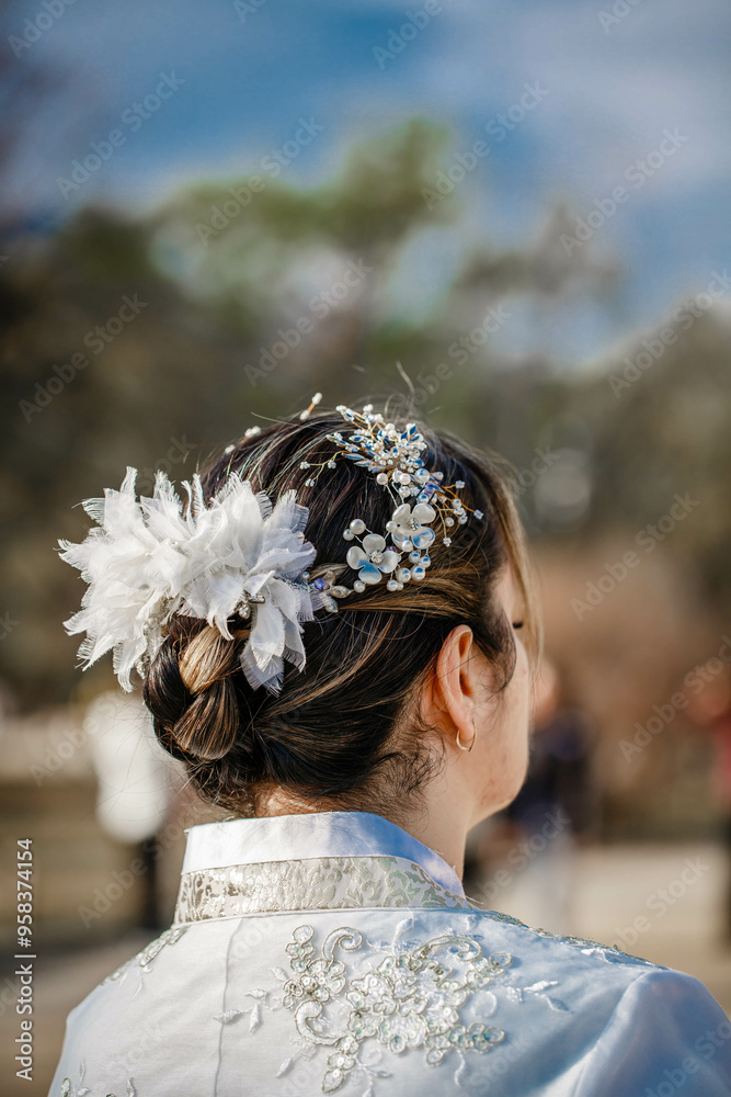 Picture of traditional Korean hairstyle for festive occasions. A girl dressed in a classic ethnic dress standing outdoor, view from the back.