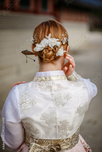 Obraz na płótnie Picture of traditional Korean hairstyle for festive occasions. A girl dressed in a classic ethnic dress standing outdoor, view from the back. w salonie