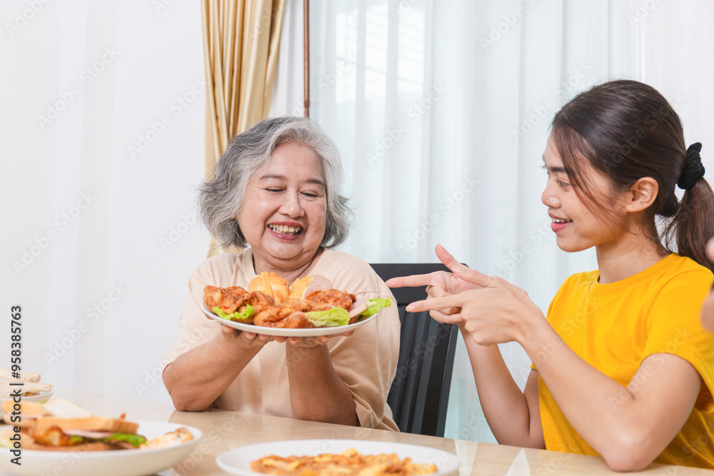 Mother and daughter having lunch, Senior woman and daughter eating foods celebrate weekend together at dining table at home Mother and daughter having lunch, Senior woman and daughter eating foods celebrate weekend together at dining table at home