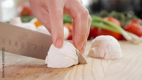 Macro. Chef slices champignons with a sharp knife on a wooden board. Preparing salads, mini pizzas with mushrooms, pie, snacks. Healthy eating concept, close-up, front view photo